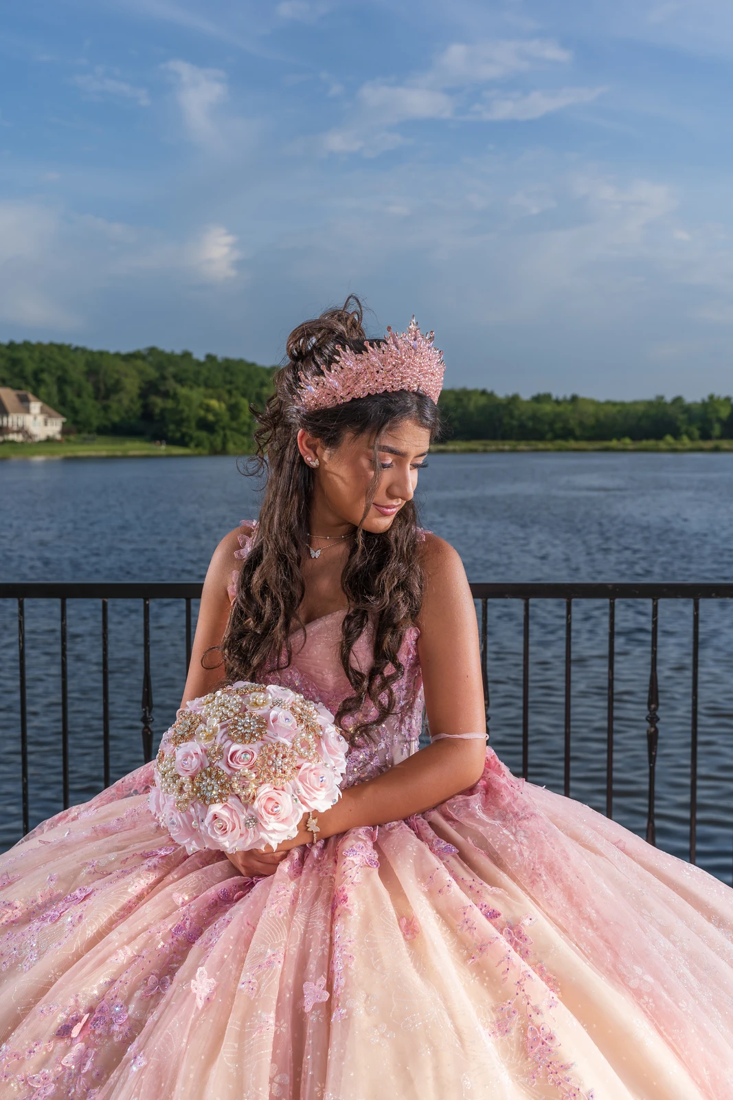 Quinceañera portrait in Kansas City by the lake wearing pink dress and holding bouquet