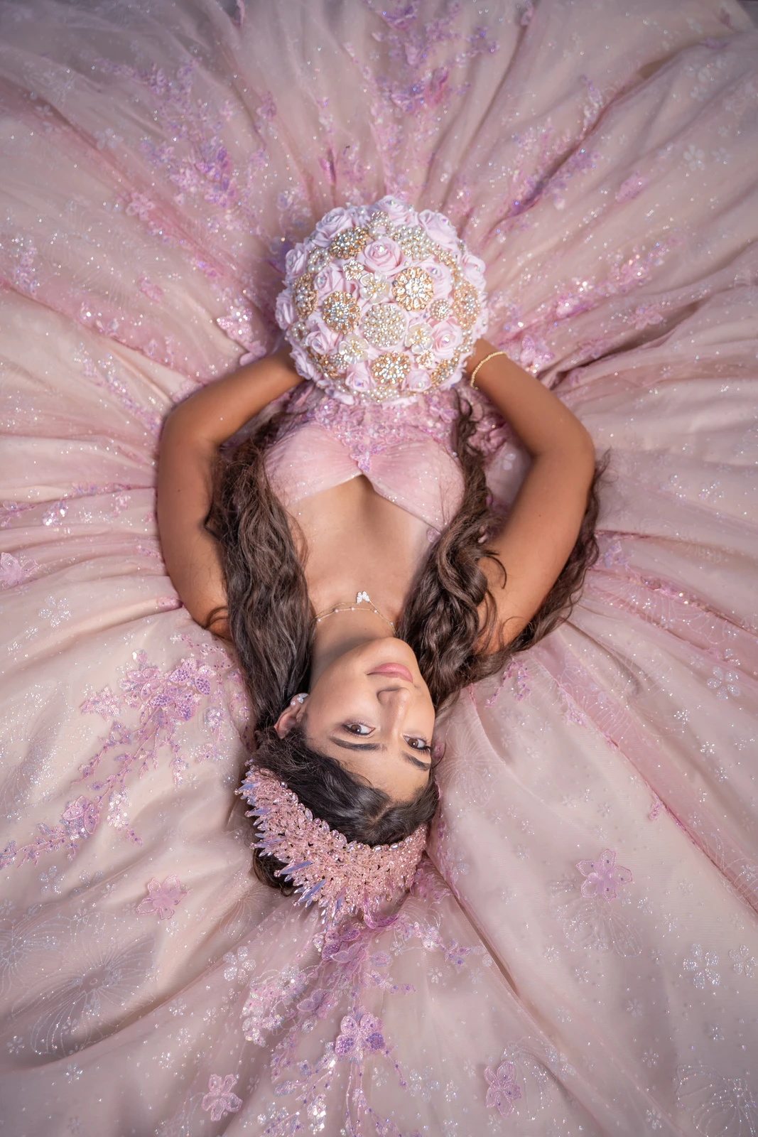 Creative top view quinceañera portrait showing pink dress spread with bouquet