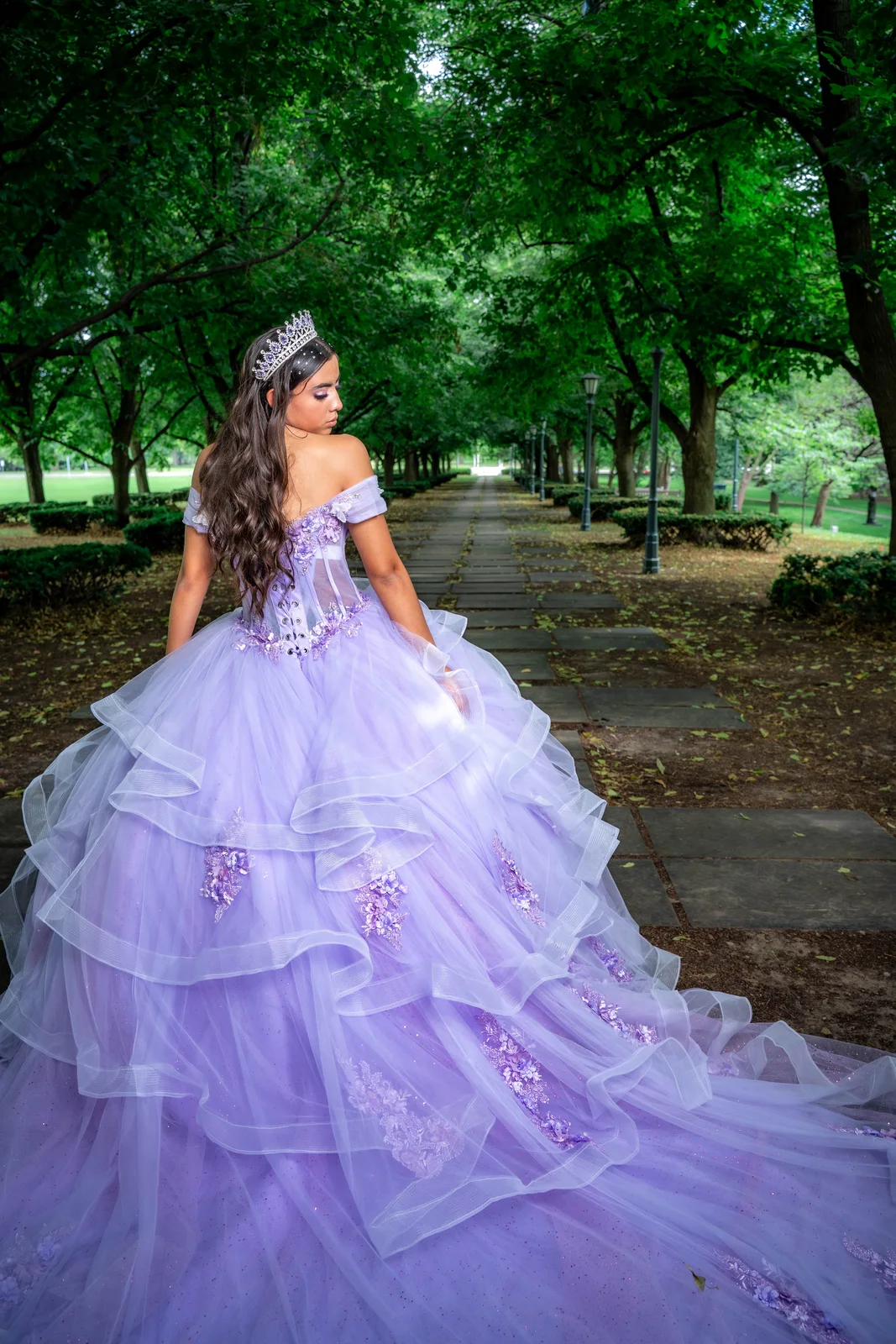 Quinceañera portrait from behind showing long purple dress train in park by Nelson-Atkins Museum of Art