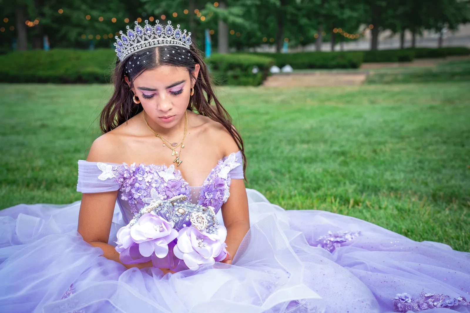 Kansas City quinceañera sitting in purple dress holding bouquet looking down at Nelson-Atkins Museum 