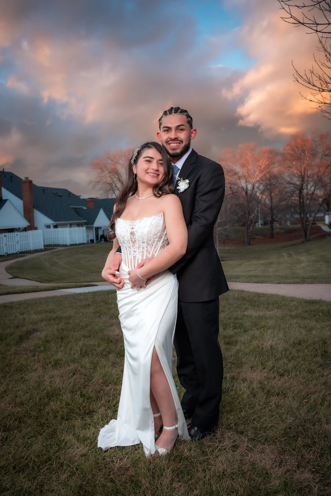 Full body wedding portrait of bride and groom smiling during sunset in Kansas City neighborhood