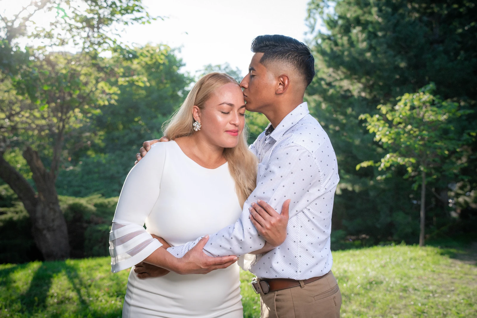 Groom kissing bride on forehead during outdoor wedding portrait in Kansas City