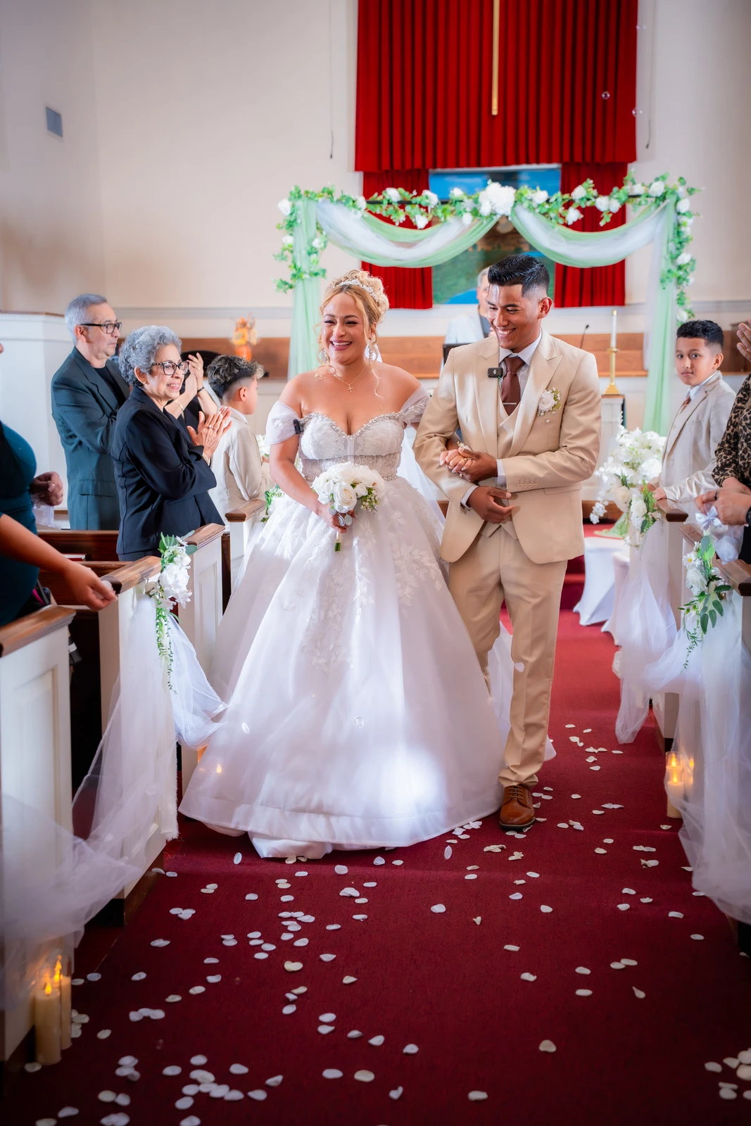 Bride and groom walking down aisle after wedding ceremony with guests celebrating