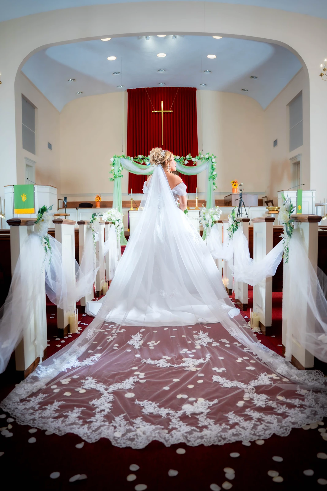 Bride standing in church showing long wedding dress train during ceremony in Kansas City