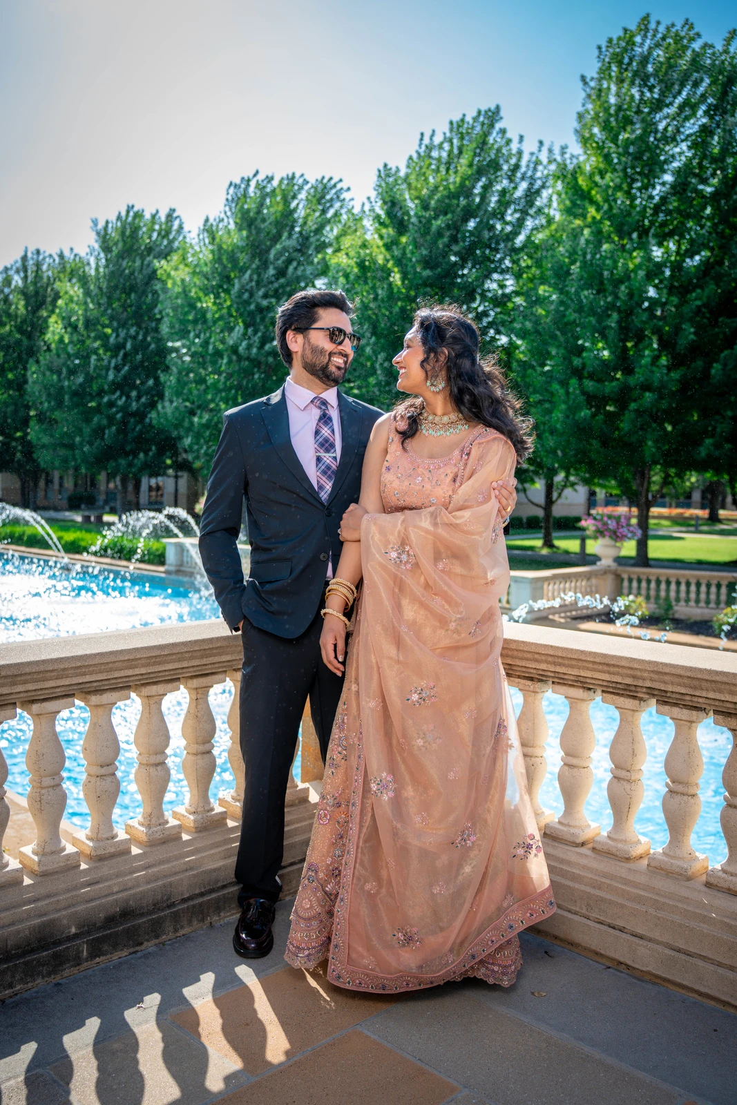 Indian wedding couple smiling together during outdoor portrait session by fountain in Kansas City
